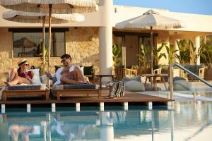 Ein Mann und eine Frau, die auf Stühlen neben einem Pool sitzen in der Unterkunft Asterion Suites & Spa - Designed for Adults in Gerani Chania