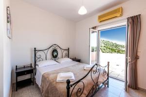 ein Schlafzimmer mit einem großen Bett und einem Balkon in der Unterkunft Olive Garden Vila in Exopoli