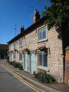 una casa de ladrillo con puertas azules y ventanas en una calle en The Cottages - Sherwood Forest, en Edwinstowe