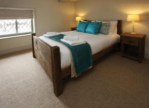 a bedroom with a large bed with blue pillows at The Cottages - Sherwood Forest in Edwinstowe