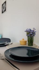 una mesa con placas negras y un jarrón de flores en Vintage Anna Apartment, en Kuldīga