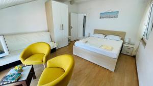 a bedroom with a bed and two yellow chairs at Apartments Danijela in Lumbarda +38 photos