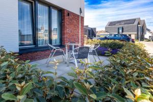 a patio with two chairs and a table in front of a building at Roosjesweg 2 Luxe gastenkamer 400 meter van strand met parkeerplaats in Domburg