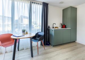 a room with a table and chairs and a kitchen at Roosjesweg 2 Luxe gastenkamer 400 meter van strand met parkeerplaats in Domburg