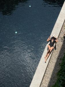una donna sdraiata sul bordo di una piscina d'acqua di Lamphu House Chiang Mai - SHA Extra Plus Certified a Chiang Mai