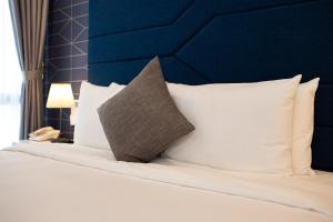 a bed with white pillows and a blue headboard at HÔTEL De SOURIANT Central Hanoi in Hanoi