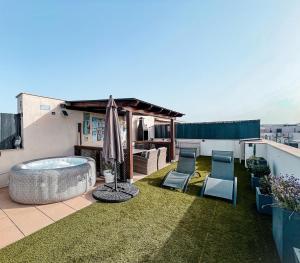 a patio with a hot tub and chairs on a roof at Sunset Deluxe con jacuzzi, piscina y barbacoa in Calafell