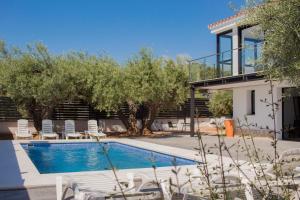 a swimming pool with chairs and a house at Villa de lujo EL MIRADOR in L'Ampolla