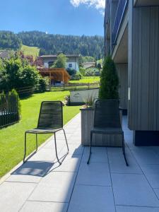 zwei Stühle auf einer Terrasse neben einem Haus in der Unterkunft Simple Life Apartments in Rauris