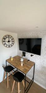 een tafel met twee stoelen en een klok aan een muur bij Studio duplex face à la mer in Guidel +16 foto's
