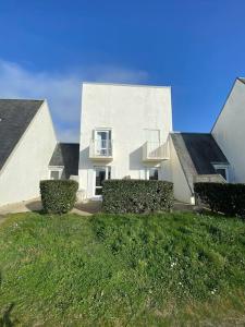 un bâtiment blanc avec des buissons devant lui dans l'établissement Studio duplex face à la mer, à Guidel