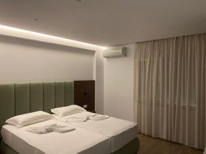 a bedroom with a large bed with a green headboard at Eval Hotel in Sarandë