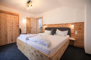 a bedroom with a large bed with white sheets at Landhaus Gasser in Wenns