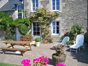 a patio with a picnic table and chairs and flowers at Gite de La Caminais in Pleurtuit