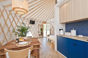 a kitchen and dining room with a wooden table and blue cabinets at JURTLANDIA jurta BOHO in Lubiatowo