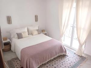 a white bedroom with a large bed and a window at NUEVA NERJA Pueblo Andaluz Casa Grafton in Nerja