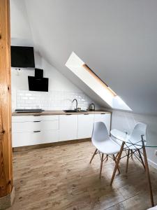 a kitchen with white cabinets and a table and chairs at Willa Azul - Podgrzewany basen, klimatyzacja w całym obiekcie in Sarbinowo
