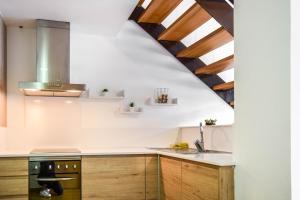 - une cuisine avec des murs blancs et des placards en bois dans l'établissement Loft Besalú alojamiento céntrico y acogedor, à Besalú