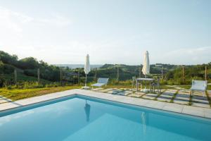 una piscina con 2 sillas, una mesa y sombrillas en Villa Ribella - Family Apartment, en San Damiano dʼAsti