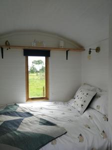 a bed in a room with a window at Sunny Mount Shepherd's Hut in Long Marton