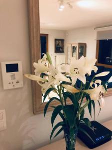 un vase de fleurs blanches sur une table avec un miroir dans l'établissement La Clé de la Forêt, à Tervuren