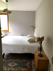 een slaapkamer met een wit bed en een tafel met een lamp bij La Clé de la Forêt in Tervuren