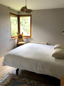 ein Schlafzimmer mit einem großen weißen Bett und einem Fenster in der Unterkunft La Clé de la Forêt in Tervuren