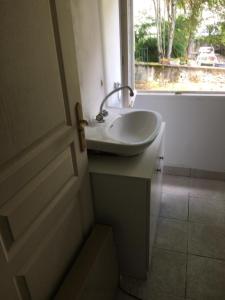 ein Bad mit einem Waschbecken und einem Fenster in der Unterkunft Appartement L Eiffel in Coulonges