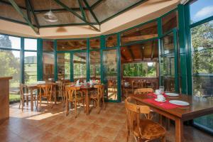 un restaurante con mesas y sillas de madera y ventanas en HOTEL PALACIO DE FIAME, en Verdicio