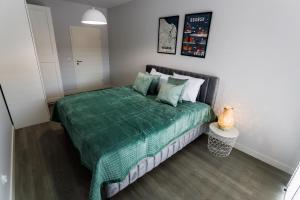 a bedroom with a bed with a green comforter at Apartamenty Svager in Gdańsk