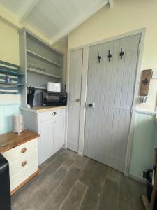 a small kitchen with white cabinets and a door at Morvin Self-Catering in Finstown