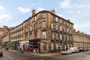 a large brick building on a street with parked cars at Glamorous flat near City Centre in Edinburgh