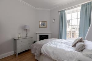 a white bedroom with a bed and a window at Glamorous flat near City Centre in Edinburgh