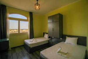 a bedroom with two beds and a window with the beach at Sahl Hasheesh, El Andalous by All View apartements in Hurghada