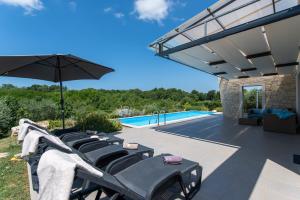 諾維格勒半島的住宿－Villa Leandra，一组椅子和一把遮阳伞,位于游泳池旁