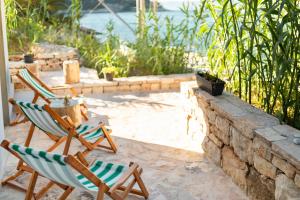 Orsula's Beach House في فيلا لوكا: كرسيان باحة يجلسون بجوار جدار حجري