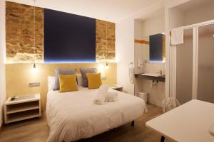 um quarto com uma cama branca e almofadas amarelas em Pensión Aia em San Sebastián