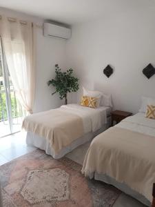 two beds in a room with white walls at NUEVA NERJA Pueblo Andaluz Casa Grafton in Nerja