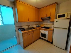 małą kuchnię z drewnianymi szafkami i białą lodówką w obiekcie Torres Montecarlo Apartmento con vistas al mar w mieście Benidorm