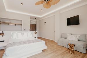 a white bedroom with a bed and a flat screen tv at Trinity Suites Ammouliani Hospitality in Ammouliani