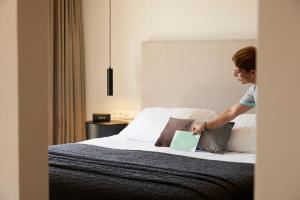 a woman standing on a bed with a laptop at Asterion Suites & Spa - Designed for Adults in Gerani