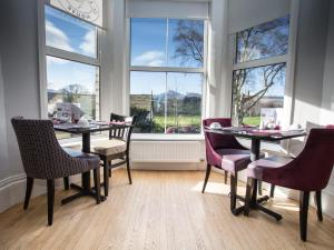 a dining room with tables and chairs and windows at LakeSide House in Keswick