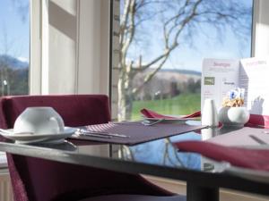 einen Tisch mit Stühlen und einen Tisch mit einem Fenster in der Unterkunft LakeSide House in Keswick