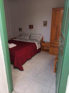sypialnia z łóżkiem z czerwonym kocem i podłogą wyłożoną kafelkami w obiekcie Dioni Lux inn 2 w mieście Pachaina