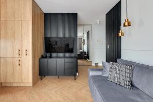 a living room with a couch and a flat screen tv at Aura 40 City Center & Free Parking by Downtown Apartments in Gdańsk