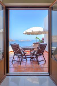 a patio with two chairs and a table with an umbrella at Stefanakis Villas - Car Included in Livadia