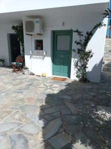 a white house with a green door and a patio at Dioni Lux inn 2 in Pachaina