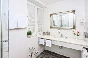een witte badkamer met een wastafel en een spiegel bij Park Hotel Laim Serviced Apartments in München
