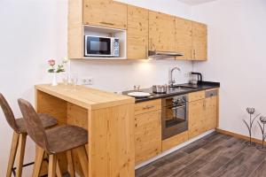 uma cozinha com armários de madeira e um balcão com um lavatório em Park Hotel Laim Serviced Apartments em Munique