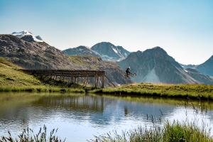 une personne voyageant à vélo au-dessus d'un pont sur une rivière dans l'établissement Charmant studio 2 personnes, rénové, vue sur le lac du Chevril, à Tignes